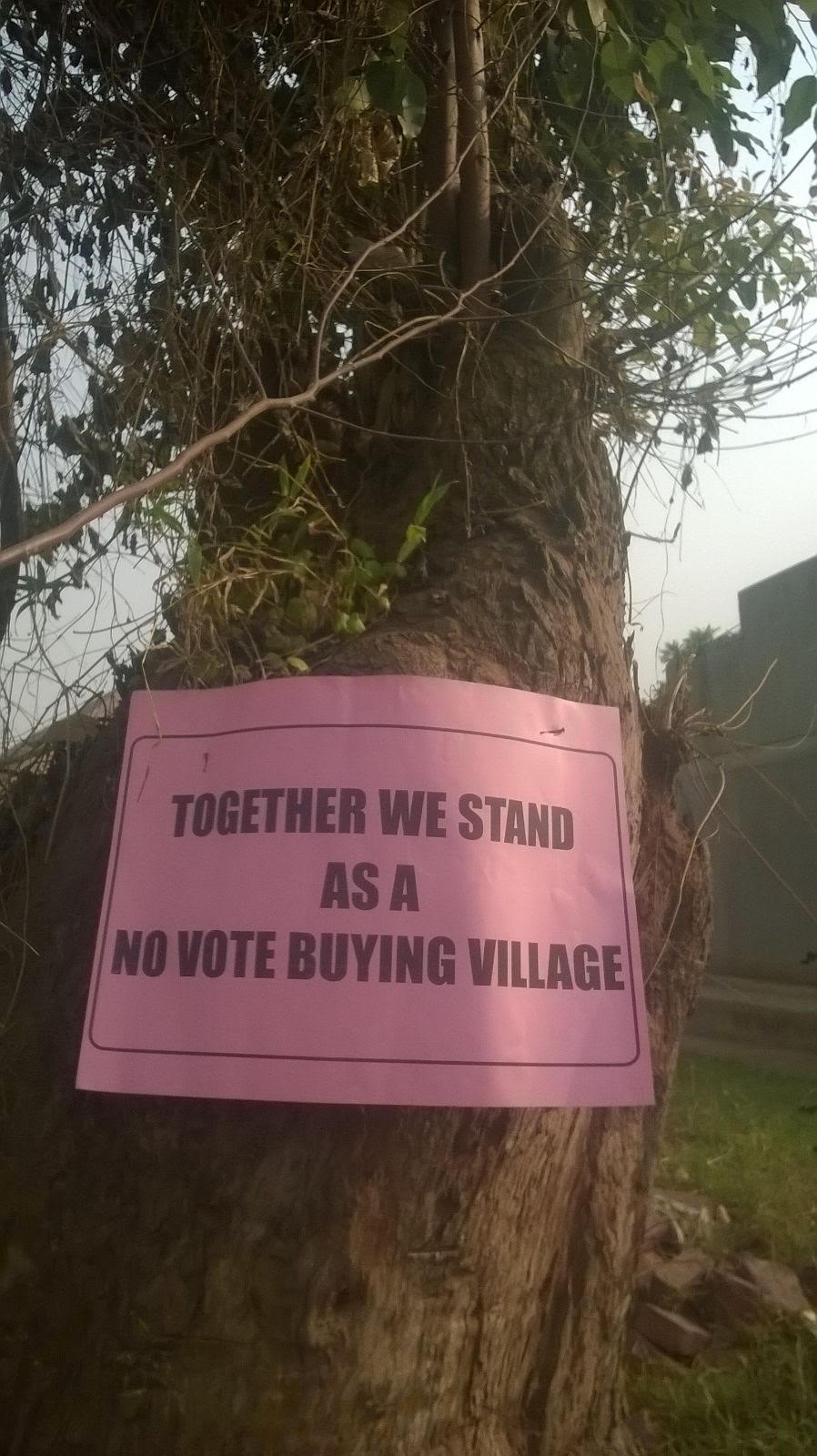 Photo of anti-vote buying poster in Ugandan village attached to a tree.