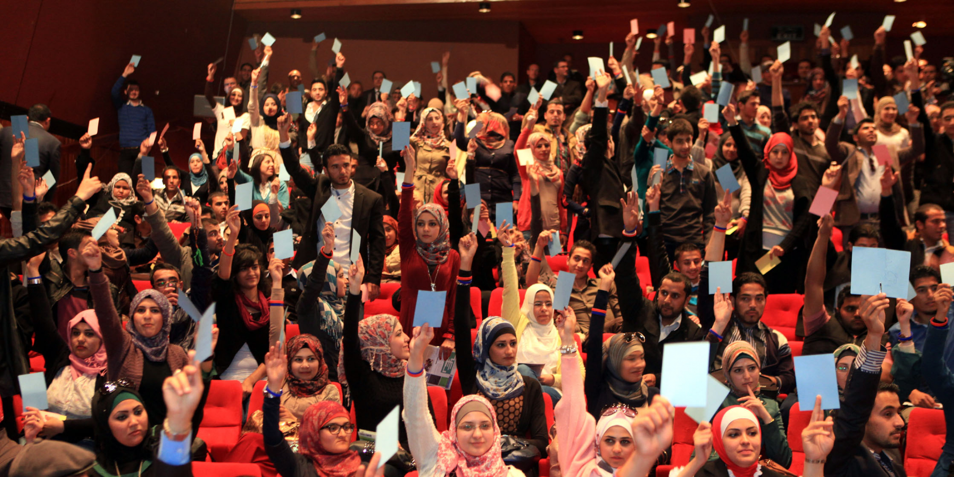 NDI Debate-Audience hold up cards to vote for the debate team from Yarmouk University, winner of Jordan's first-ever national student debate competition_Debating on allowing parties to operate in universities.JPG