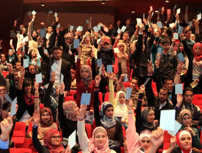 NDI Debate-Audience hold up cards to vote for the debate team from Yarmouk University, winner of Jordan's first-ever national student debate competition_Debating on allowing parties to operate in universities.JPG
