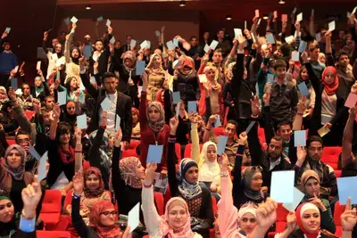 NDI Debate-Audience hold up cards to vote for the debate team from Yarmouk University, winner of Jordan&#039;s first-ever national student debate competition_Debating on allowing parties to operate in universities.JPG